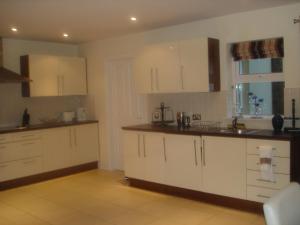an empty kitchen with white cabinets and a window at 33 ArdMullen Townhouse X Davitt's Guesthouse & Restaurant Kenmare in Kenmare +7 photos