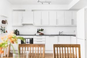 a kitchen with white cabinets and a table and chairs at Nice, Modern Apartment in Central Bergen in Bergen