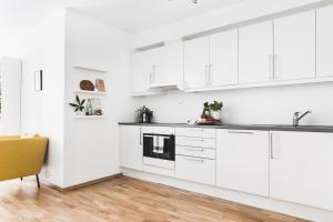 a white kitchen with white cabinets and a yellow chair at Nice, Modern Apartment in Central Bergen in Bergen