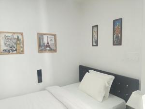 a white room with a bed and four pictures on the wall at J. I. T HOTEL in Chaltlāng