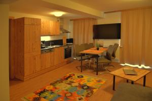 a living room with a kitchen and a table with chairs at Apartment Haus am See in Uttendorf