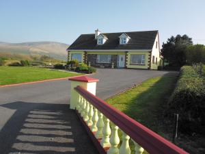 a house with a fence in front of a driveway at The Waterfront B&B in Portmagee