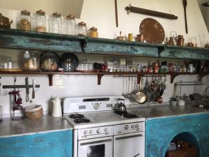 cocina con fogones y estanterías con ollas y sartenes en Estancia La Margarita en Chascomús