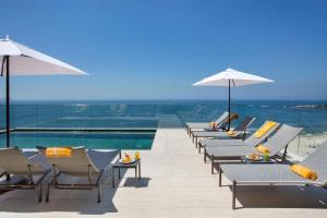 eine Reihe von Stühlen und Sonnenschirmen neben einem Pool in der Unterkunft Windsor California Copacabana in Rio de Janeiro