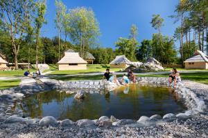 eine Gruppe von Menschen, die in einem Teich in einem Park sitzen in der Unterkunft Slovenia Eco resort in Stahovica