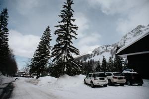 dwa samochody zaparkowane na śniegu obok domu w obiekcie Val di Luce - Interno 19 w mieście Abetone