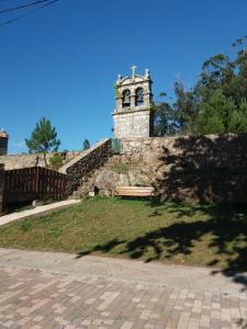 una pared de piedra con un banco y una torre de reloj en Casa Lola en Villastose