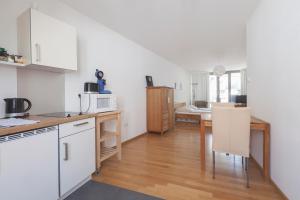 een keuken met witte kasten en een tafel met een magnetron bij Altstadtloft am Martinstor in Freiburg im Breisgau