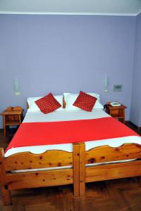 una cama de madera con almohadas rojas y blancas. en Hotel Nazionale, en Bormio