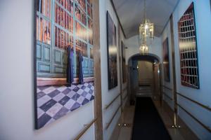 a hallway with paintings on the walls and a chandelier at Torre Argentina Relais - Residenze di Charme in Rome