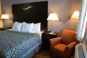 um quarto de hotel com uma cama e uma cadeira em Days Inn by Wyndham Jacksonville NC em Jacksonville