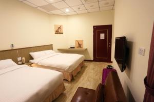 ein Hotelzimmer mit 2 Betten und einem TV in der Unterkunft ChangJu Hotel in Taitung