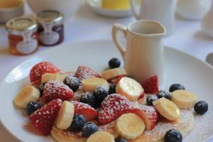 a plate of fruit on a table with a cup of coffee at Woodlands in Windermere