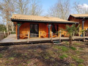 a small house with a wooden porch in a yard at Au Bois Flotté in Hourtin