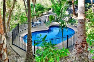 a fence around a swimming pool in a garden at The Panorama 3, Hamilton Island 2 Bedroom 2 Bathroom Ocean View Modern Apartment in Hamilton Island