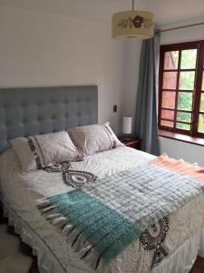 a bedroom with a bed with a blanket and a window at Departamento Pucón in Pucón