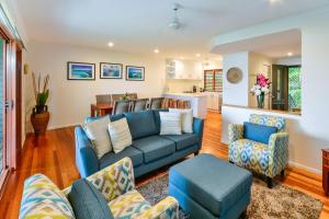 sala de estar con sofá azul y sillas en Heliconia 1 Hamilton Island 3 Bedroom Ocean Views with Golf Buggy, en Hamilton Island