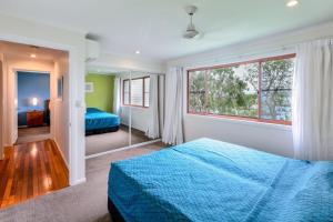 ein Schlafzimmer mit einem blauen Bett und einem großen Fenster in der Unterkunft Heliconia 1 Hamilton Island 3 Bedroom Ocean Views with Golf Buggy in Hamilton Island
