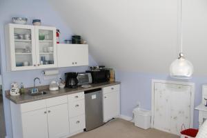 una cocina con armarios blancos y fregadero en Lavender Bay en Barnstable