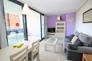 sala de estar con paredes de color púrpura, mesa y sofá en Apartamentos Gema - Gemelos 26, en Benidorm