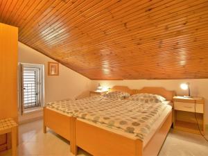 a bedroom with a large bed with a wooden ceiling at Apartments Ljubica in Barbat na Rabu