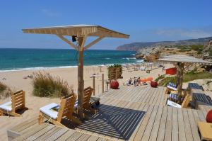a wooden deck with chairs and umbrellas on a beach at modern flat in Estoril