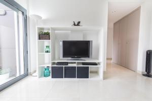 a white living room with a television on a shelf at modern flat in Estoril