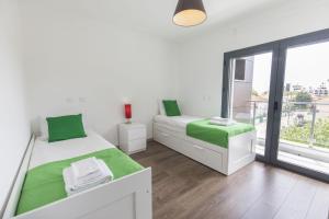 a white bedroom with two beds and a window at modern flat in Estoril