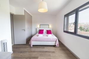 a bedroom with a bed with pink sheets and a window at modern flat in Estoril