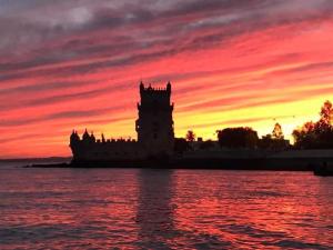 a building with a sunset in front of the water at modern flat in Estoril