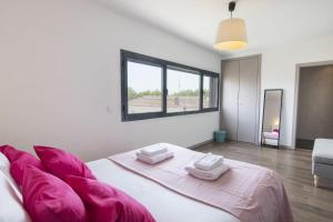 a white bedroom with a large bed with pink pillows at modern flat in Estoril