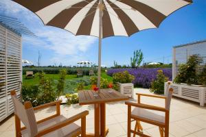 a patio with a wooden table and an umbrella at Hotel Casale Milocca in Siracusa
