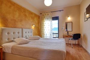 a bedroom with a bed and a desk and a window at Hotel Atlantis in Corfu
