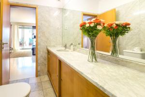 a bathroom with two vases with flowers on a counter at By the Sea Apartment with Large Private Terrace in Matosinhos