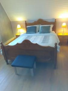 a bedroom with a large wooden bed with a blue bench at Chez Nicole in Marconne