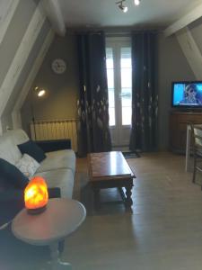 ein Wohnzimmer mit einem Sofa, einem Tisch und einem TV in der Unterkunft Chez Nicole in Marconne