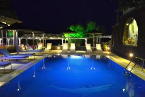 een zwembad 's nachts met stoelen en tafels bij Thousand Stars Suites&Rooms in Kamari
