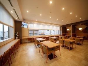 八户市多美迎本八户酒店的配有桌椅和平板电视的餐厅
