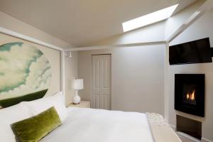 1 dormitorio con cama blanca y chimenea en Rockhouse Suites, en Healdsburg