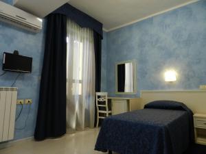 1 dormitorio con paredes azules, 1 cama y espejo en Hotel Air Palace Lingotto, en Turín