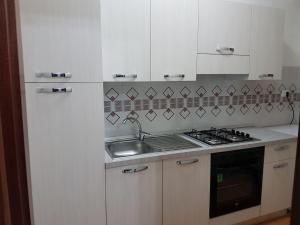 a kitchen with white cabinets and a sink and a stove at Il Sole di Nonno Ciccio in Alcamo Marina