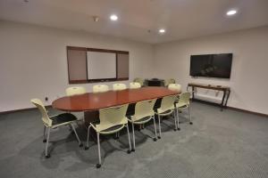 a conference room with a table and chairs and a screen at Ivy Court Inn and Suites in South Bend