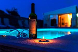 una bottiglia di vino e bicchieri accanto a una candela di Rural house Mudrinic "Ivini dvori" a Bogatić