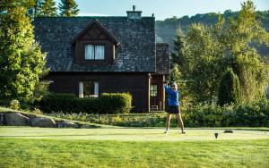 a man swinging a golf club in front of a house at Chalets Royal Laurentien in Saint-Faustin