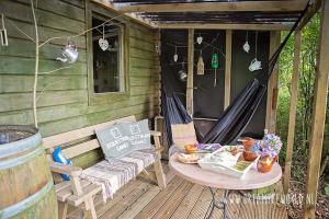 eine Veranda mit einer Schaukel, einem Tisch und einer Hängematte in der Unterkunft Het Swadde huisje in Twijzelerheide