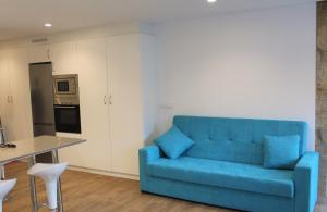un sofá azul en una sala de estar con cocina en Apartamento luaS, en Santiago de Compostela