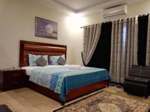 ein Schlafzimmer mit einem Bett, einem Stuhl und Vorhängen in der Unterkunft Seaview Lodge Guest House in Karatschi
