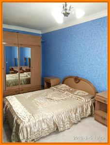 a bedroom with a bed and a blue wall at Уютная 1-квартира в центре города in Shakhty