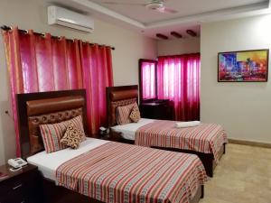 two beds in a room with red curtains at Seaview Lodge Guest House in Karachi +51 photos