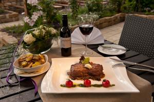einen Tisch mit einem Teller Essen und einem Glas Wein in der Unterkunft Weingut Sandwiese Winzerhotel in Worms